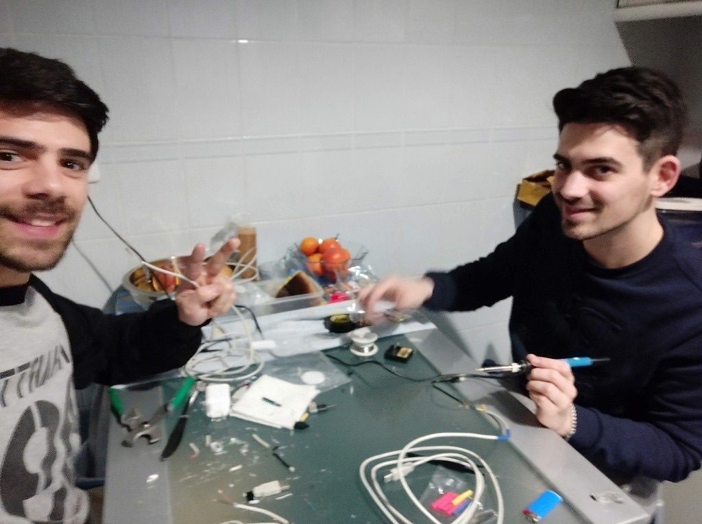 Two friends soldering electronics on a kitchen table